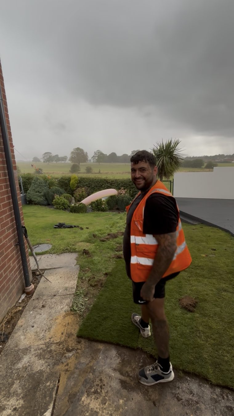 Ashley Ditta, owner of AD Outdoor Solutions, laying new turf on a customer's lawn